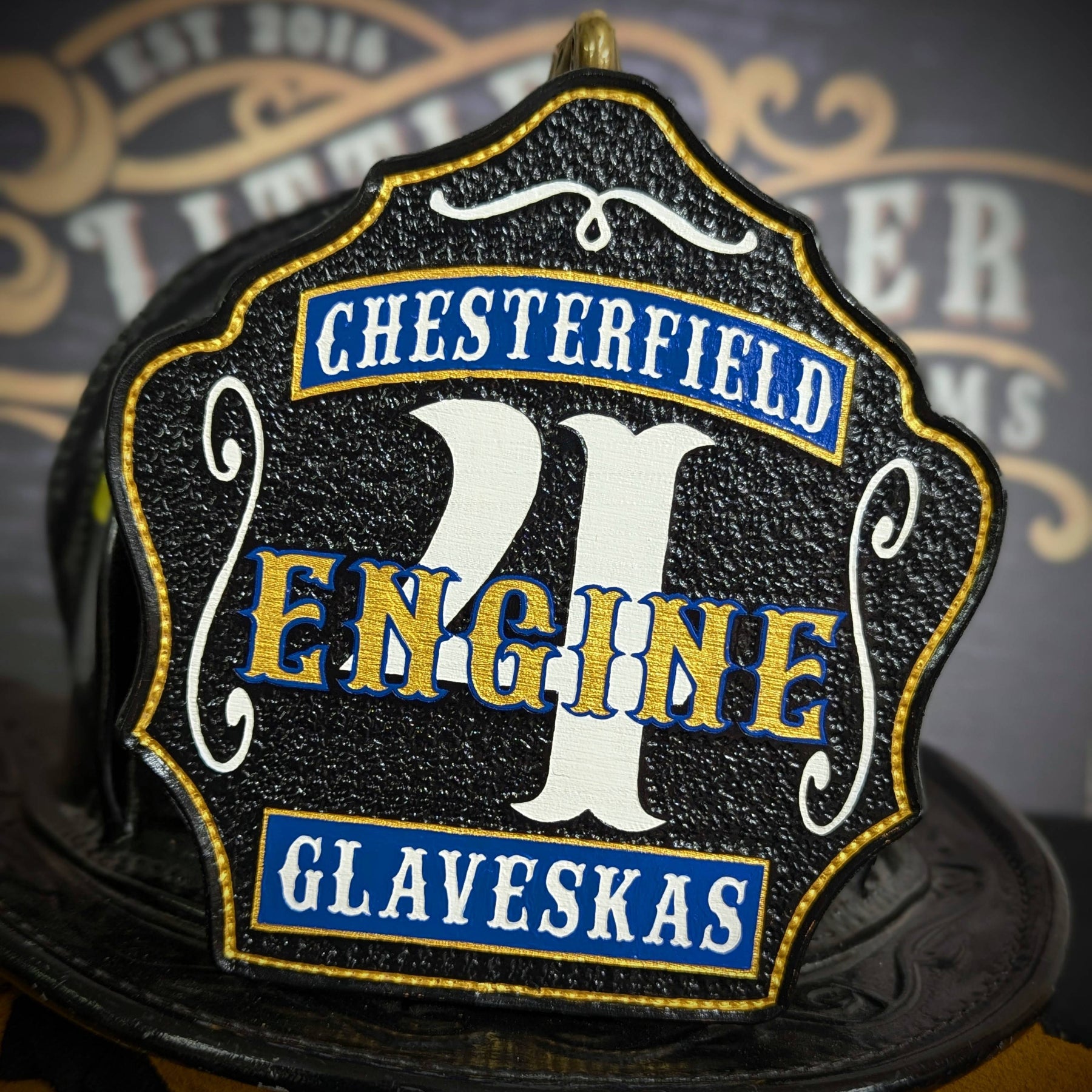 Black leather firefighter helmet shield with bold white number 4 and blue engine lettering, custom fire department gear.