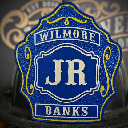 Blue leather firefighter helmet shield with bold white JR letters, Wilmore banner at the top, Banks nameplate at the bottom, and yellow decorative accents.
