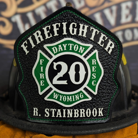 Custom leather firefighter helmet shield with Maltese cross design and fire department details.