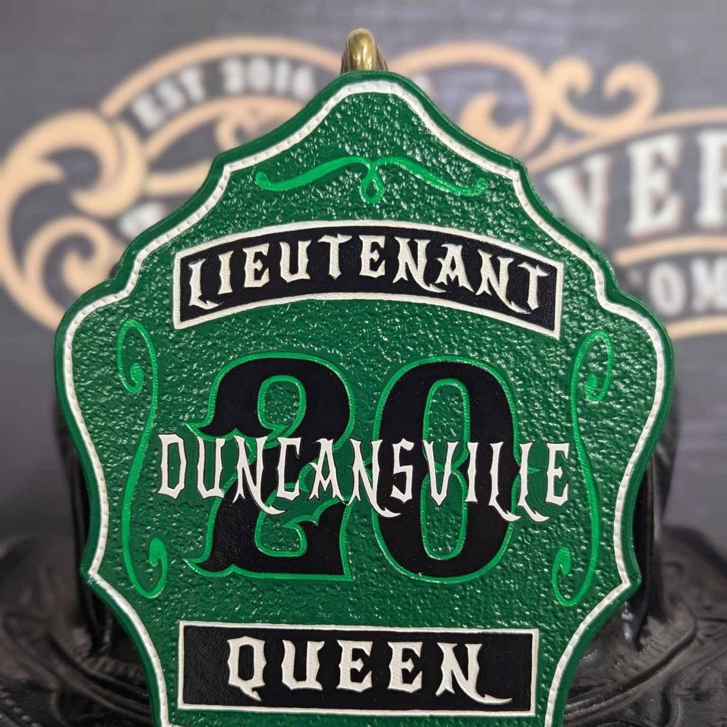 Green-accent lieutenant leather firefighter helmet shield with arched title on black.