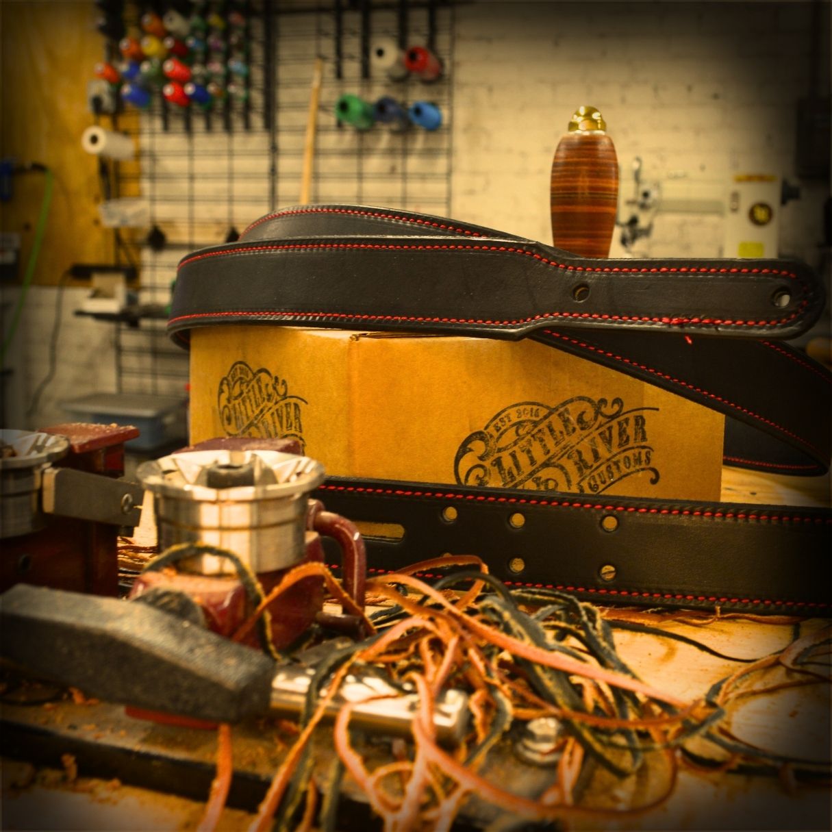 Little River Customs workshop image with leather strap and branded box representing future innovation in firefighter gear