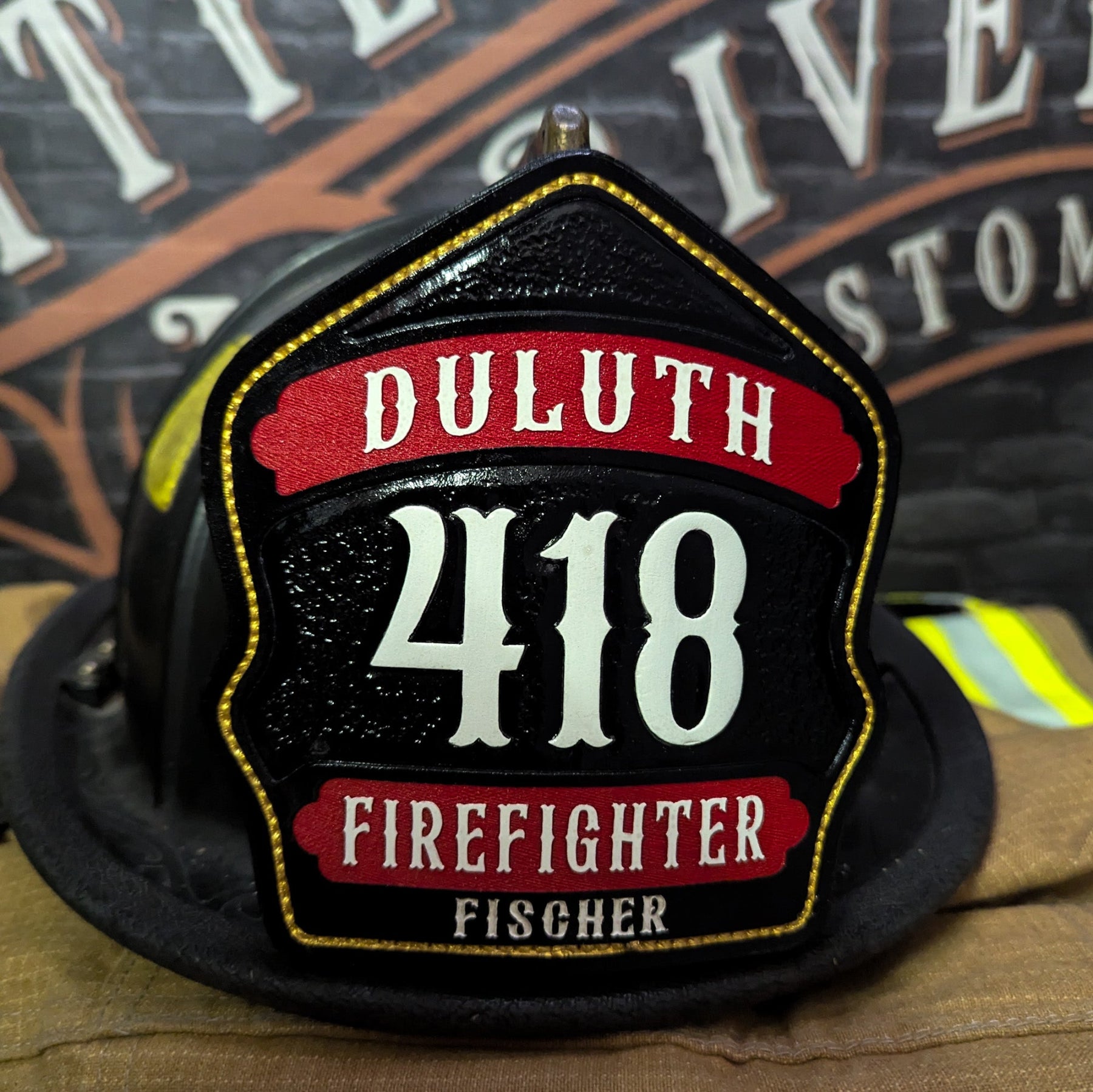 Leather firefighter helmet shield with deep red numerals and gold accents on a textured black field.