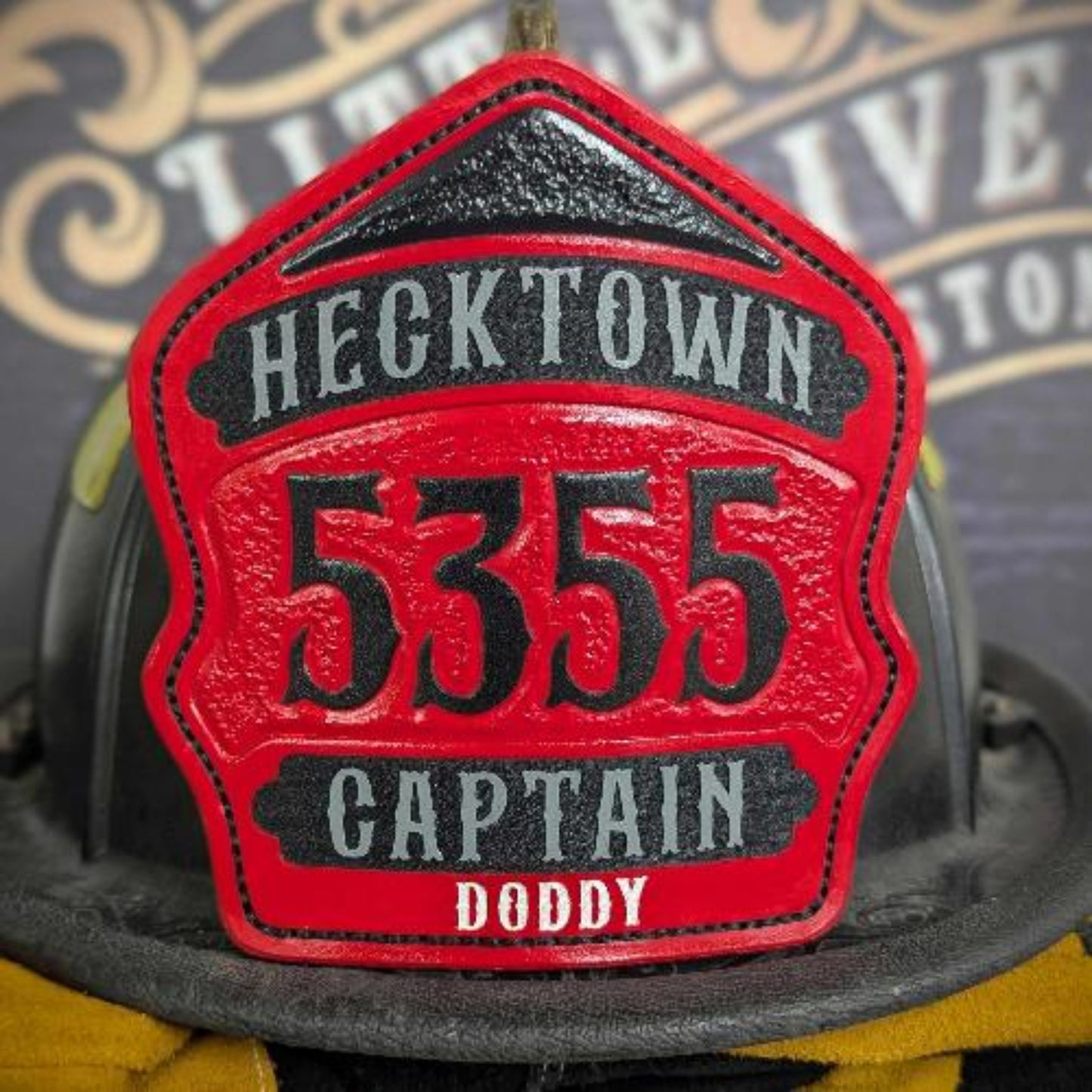 Red captain-style leather firefighter helmet shield with black panels and large numerals—hand-painted and mounted on a helmet.