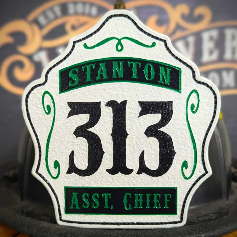 Standard Issue custom leather firefighter helmet shield for Assistant Chief in white with black numbers, green trim, and department text.