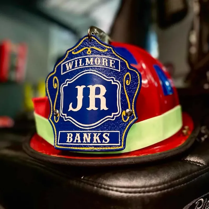 Standard Issue custom leather firefighter helmet shield in blue with white lettering mounted on a red firefighter helmet.