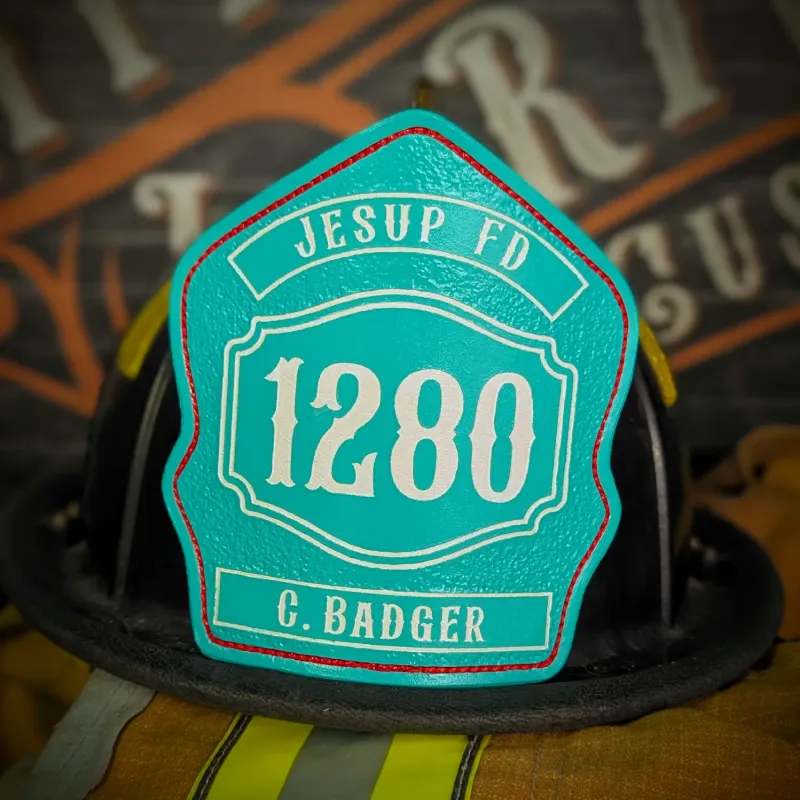 Standard Issue custom leather firefighter helmet shield in teal with white numbers, department text, and red trim accent.