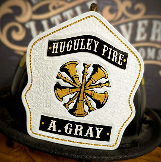 White leather firefighter helmet shield with gold bugle emblem and black title/name banners—hand-painted and mounted on a helmet.