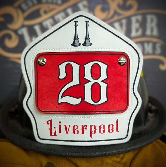 White leather firefighter helmet shield with red inset panel and large numerals, twin bugle icons—hand-painted and mounted on a helmet.