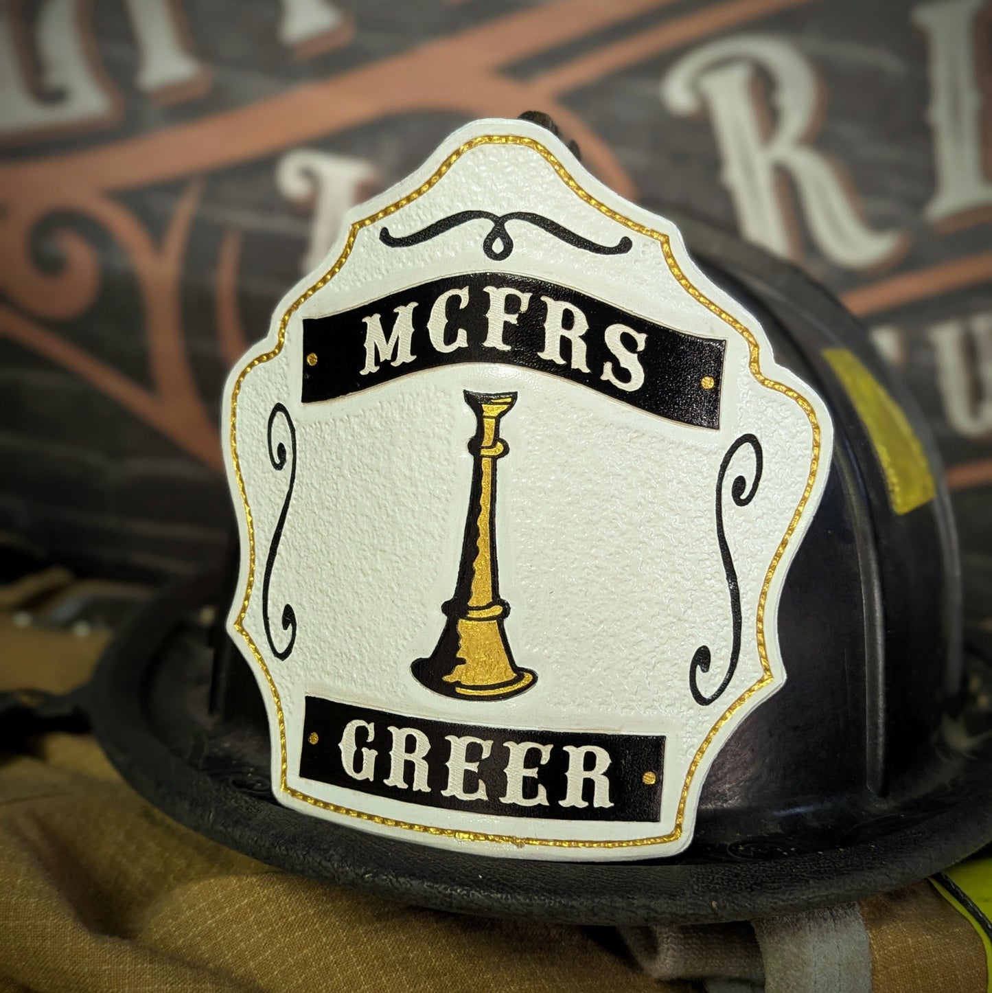 White leather firefighter helmet shield with single gold bugle and black title/name banners—hand-painted and mounted on a helmet.