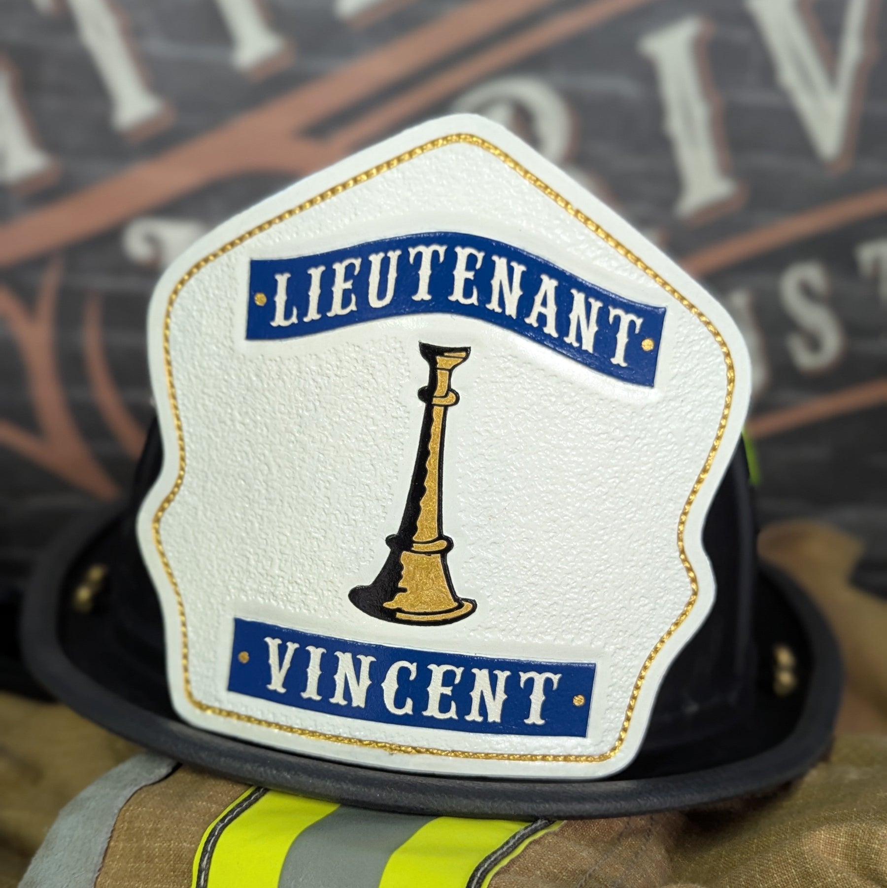 White leather firefighter helmet shield with single gold bugle and blue title/name banners—hand-painted and mounted on a helmet.