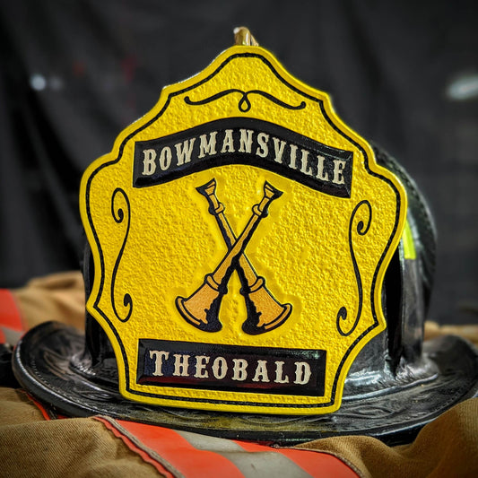 Yellow leather firefighter helmet shield with crossed gold bugles and black banners—hand-painted and mounted on a helmet.
